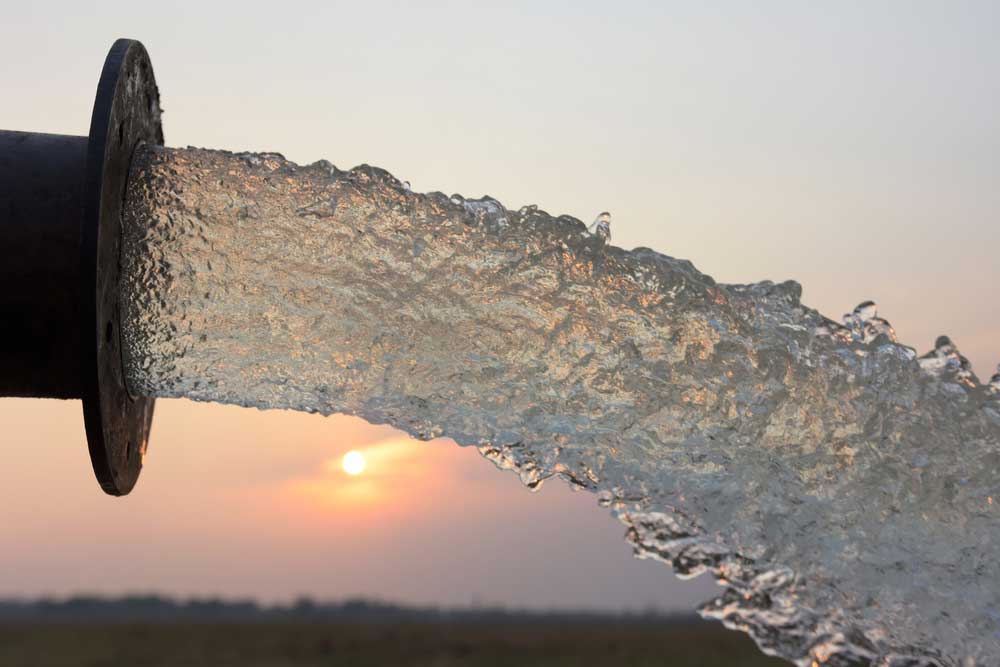 Water Flowing From A Pipe On Sunset Background