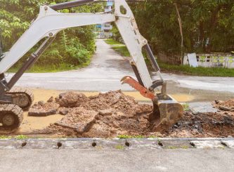 Backhoe dig repair broken water line pipe main plumbing on road — Water Management Near Me in NSW
