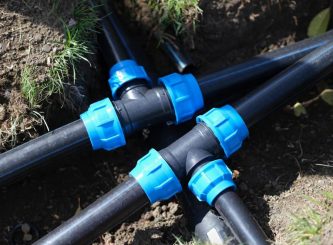 Black three way plastic water pipe on grass — Water Management Near Me in Burleigh Heads QLD